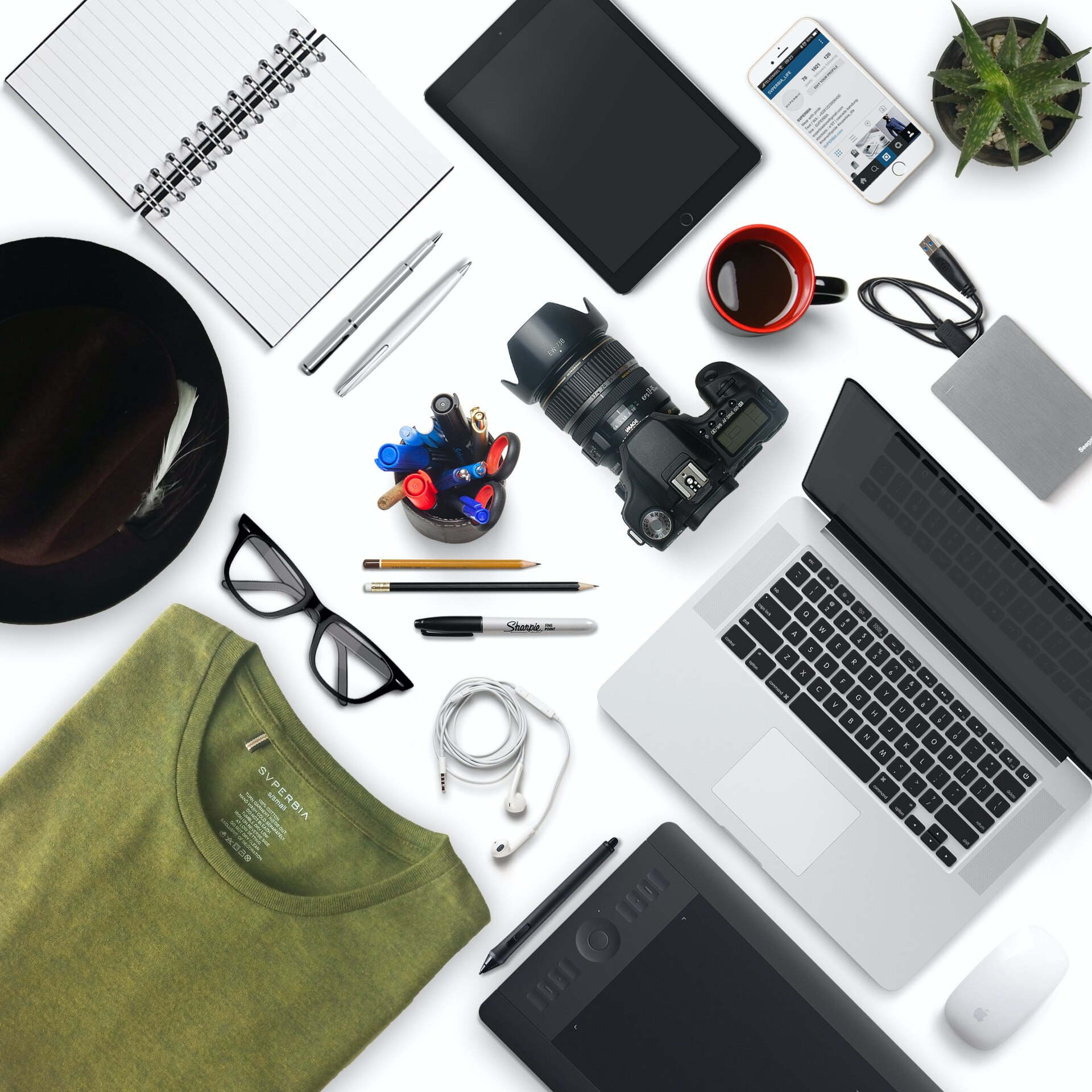 Ordinateur, appareil photo et carnet disposés sur un bureau